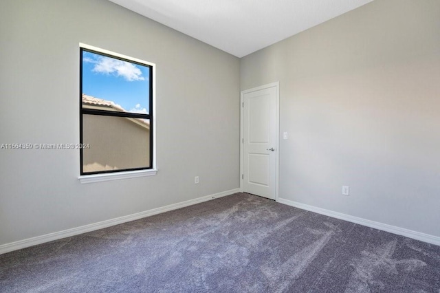 spare room featuring dark colored carpet