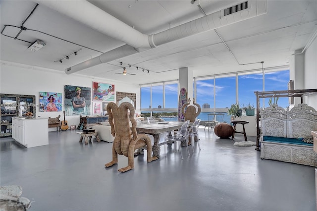 dining room featuring concrete flooring, expansive windows, a water view, and ceiling fan