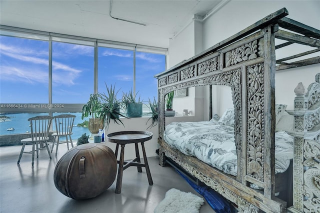 bedroom with floor to ceiling windows, a water view, and concrete flooring