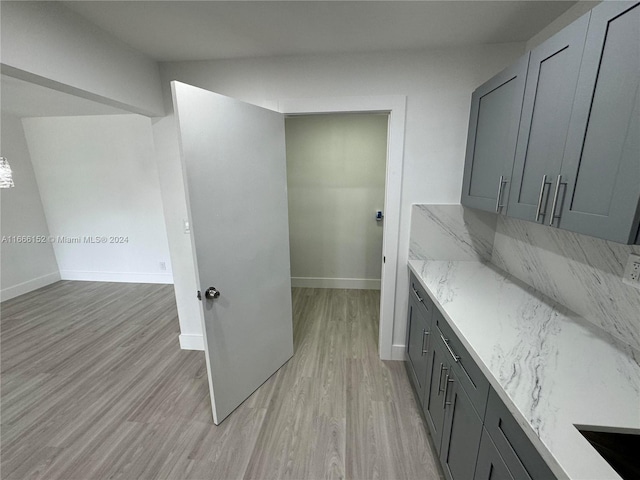 kitchen with light hardwood / wood-style flooring, light stone counters, and gray cabinets