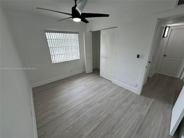 unfurnished bedroom with a closet, light wood-type flooring, and ceiling fan