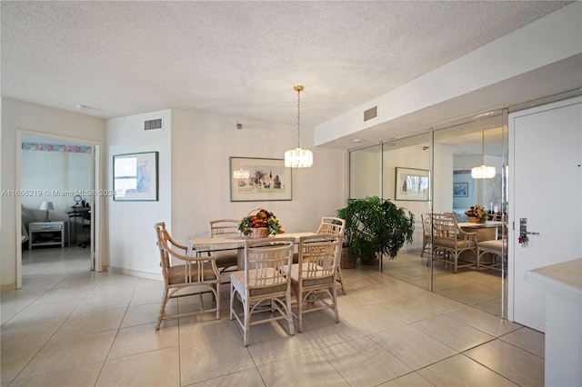 dining room with an inviting chandelier, light tile patterned floors, and a textured ceiling