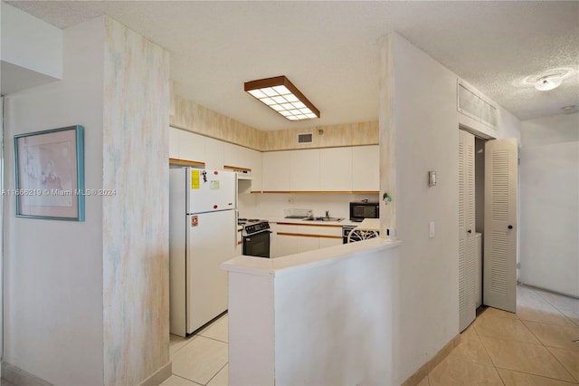 kitchen featuring kitchen peninsula, light tile patterned floors, a textured ceiling, black appliances, and sink