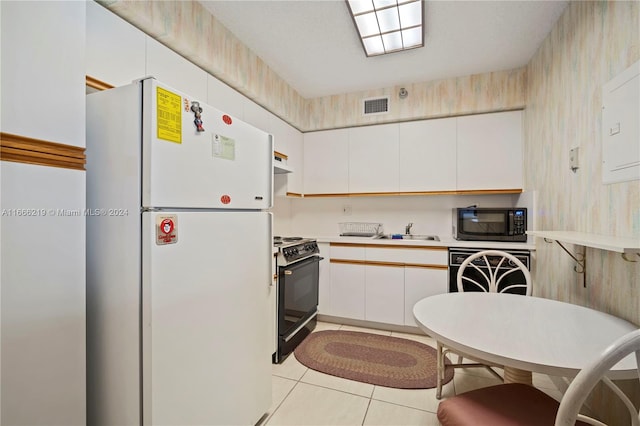 kitchen with black appliances, light tile patterned flooring, sink, and white cabinets