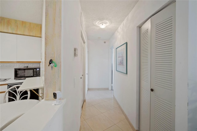 hallway featuring a textured ceiling and light tile patterned floors