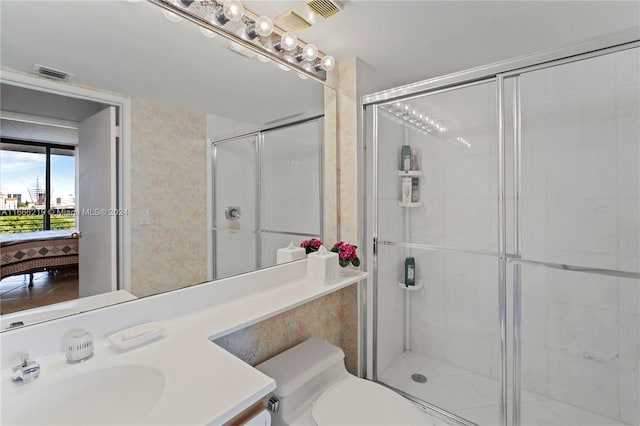 bathroom with walk in shower, vanity, and toilet