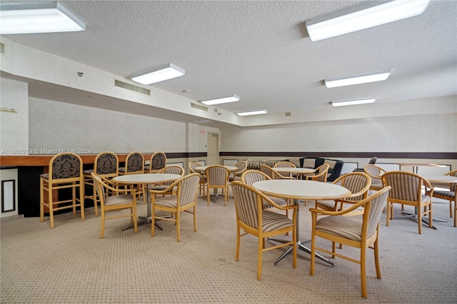 carpeted dining space with a textured ceiling