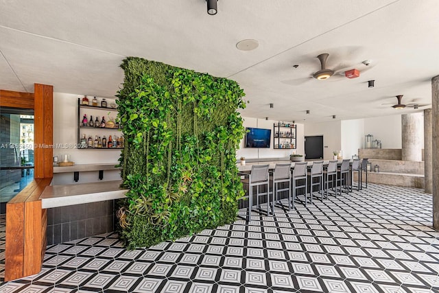 interior space with a textured ceiling, bar area, and ceiling fan