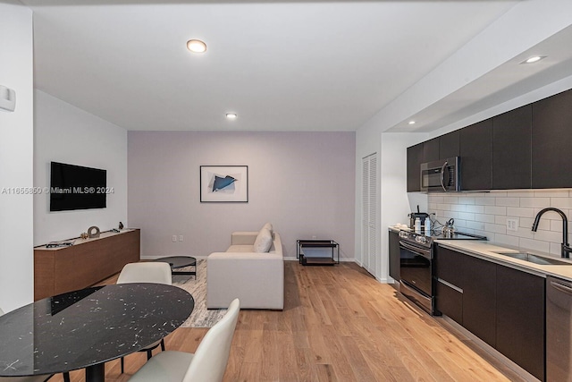 kitchen with backsplash, light hardwood / wood-style floors, appliances with stainless steel finishes, and sink