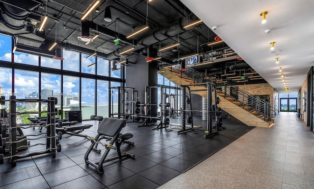 gym featuring a towering ceiling, floor to ceiling windows, and a wealth of natural light