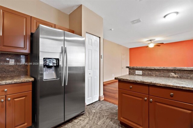 kitchen with ceiling fan, light stone counters, tasteful backsplash, wood-type flooring, and stainless steel refrigerator with ice dispenser