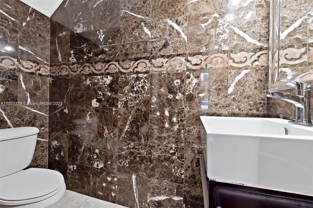 bathroom with vanity, tile walls, and toilet