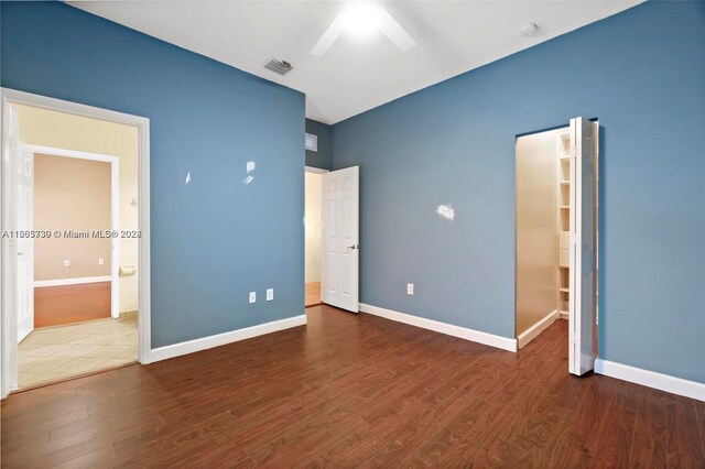 unfurnished bedroom featuring ceiling fan, dark hardwood / wood-style flooring, and a spacious closet