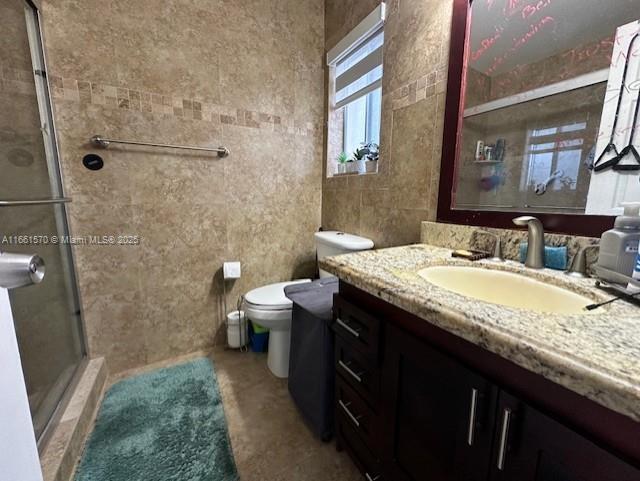 bathroom with vanity, toilet, and a shower with door