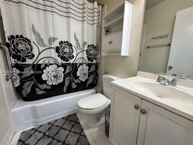 full bathroom featuring toilet, vanity, tile patterned floors, and shower / tub combo with curtain