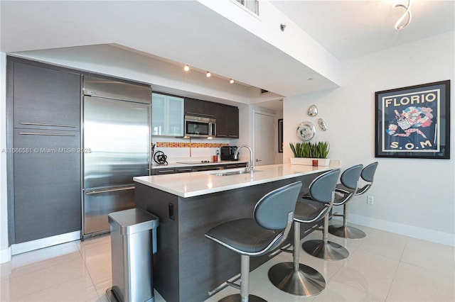 kitchen featuring a breakfast bar, sink, light tile patterned floors, appliances with stainless steel finishes, and kitchen peninsula