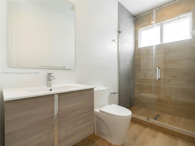 bathroom featuring hardwood / wood-style floors, walk in shower, vanity, and toilet