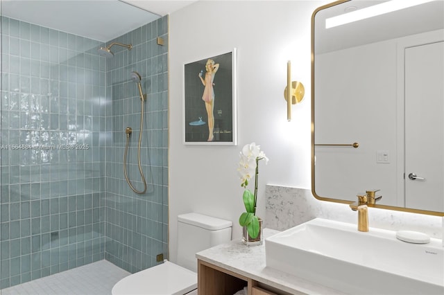 bathroom featuring vanity, tiled shower, and toilet