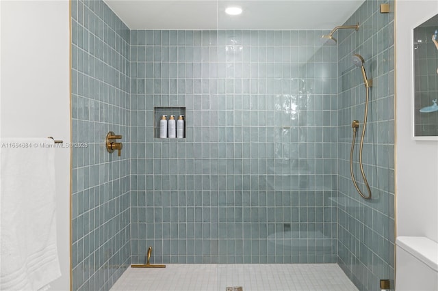 bathroom featuring tiled shower and toilet