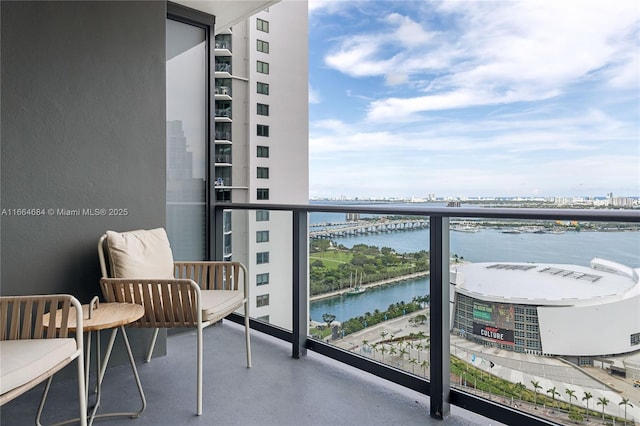 balcony featuring central air condition unit and a water view