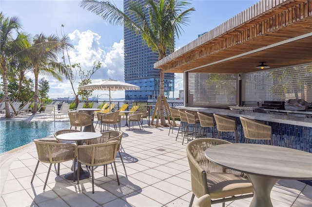 view of patio / terrace featuring a community pool, ceiling fan, and exterior bar