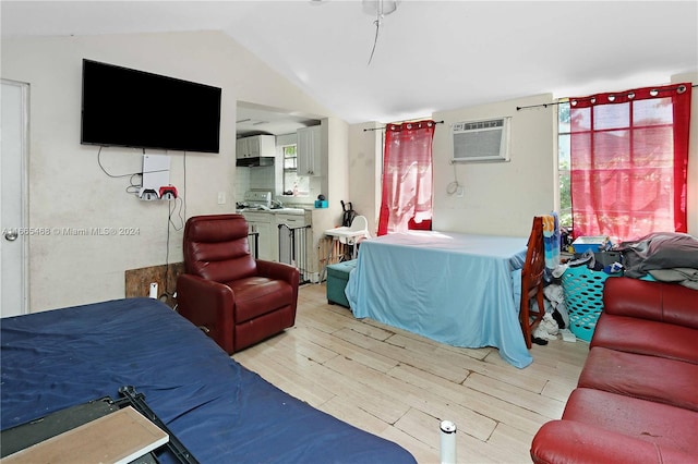 interior space with light hardwood / wood-style flooring, vaulted ceiling, washer / dryer, and an AC wall unit