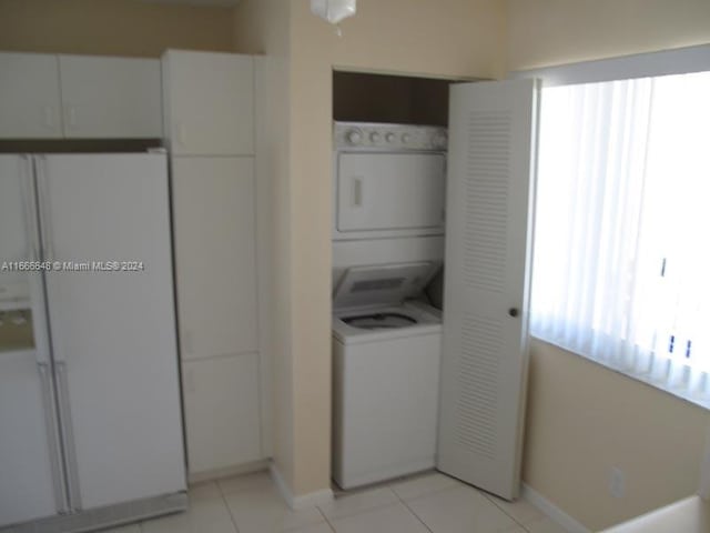 laundry room with stacked washing maching and dryer and light tile patterned flooring