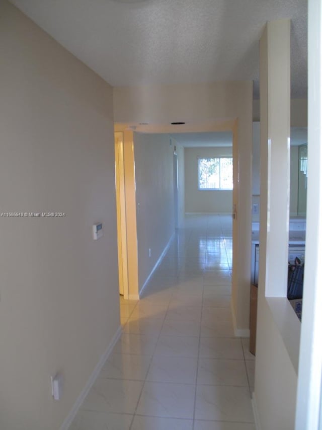 hall featuring a textured ceiling and light tile patterned flooring