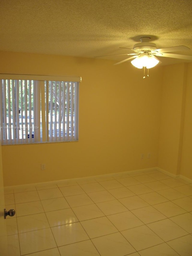 spare room featuring a textured ceiling, light tile patterned flooring, and ceiling fan