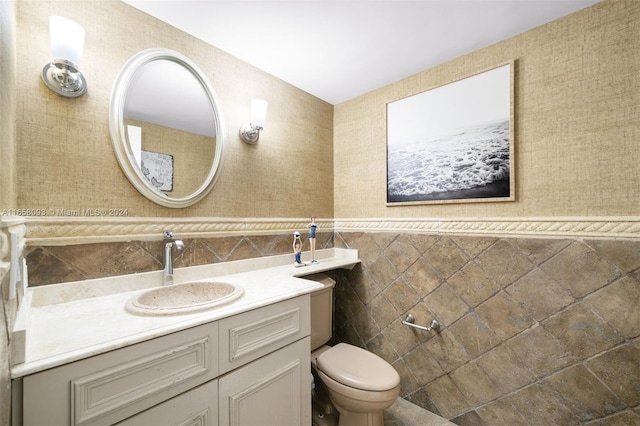 bathroom featuring vanity, tile walls, and toilet