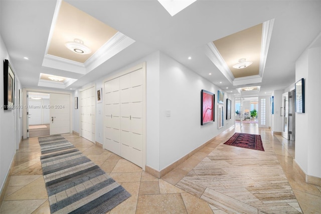 corridor with ornamental molding and a tray ceiling