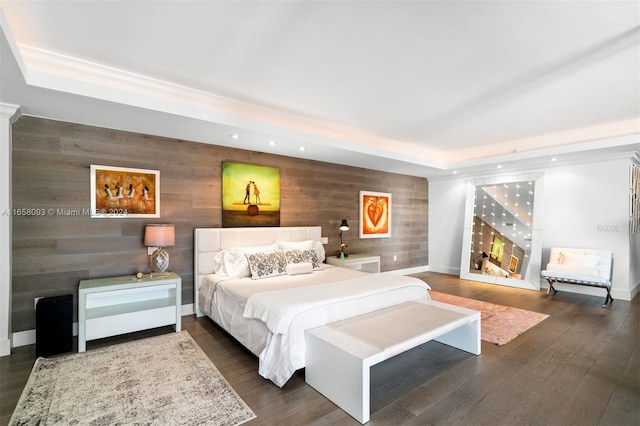 bedroom featuring wooden walls, a tray ceiling, and dark hardwood / wood-style flooring