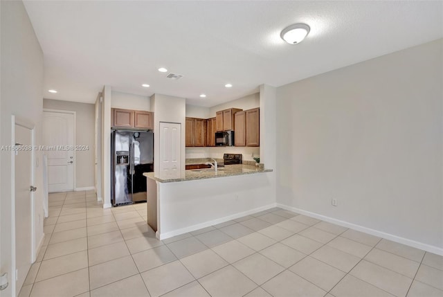 kitchen featuring light stone counters, light tile patterned flooring, sink, kitchen peninsula, and black appliances