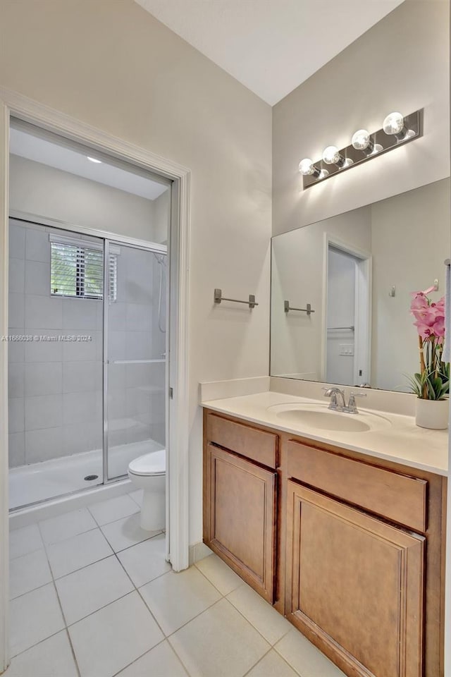 bathroom with vanity, a shower with shower door, toilet, and tile patterned flooring