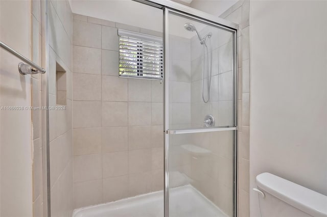 bathroom with toilet and a shower with shower door