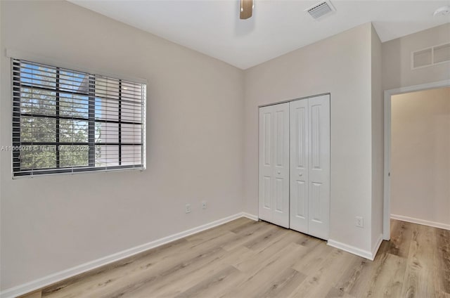 unfurnished bedroom with ceiling fan, light wood-type flooring, and a closet