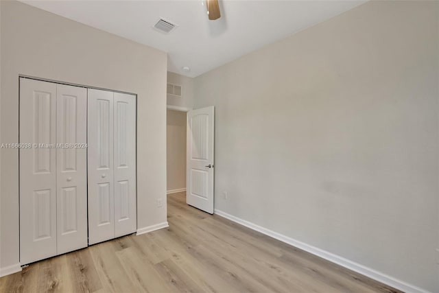 unfurnished bedroom with light wood-type flooring, ceiling fan, and a closet