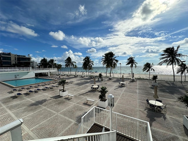 view of swimming pool with a patio, a view of the beach, and a water view