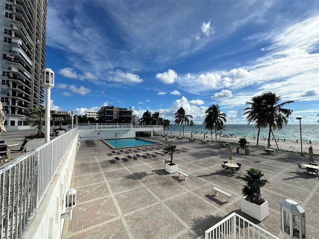 view of pool with a view of the beach, a water view, and a patio area