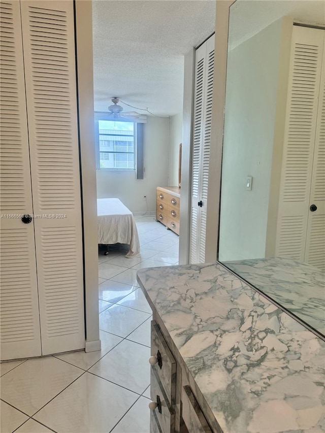 bedroom with multiple closets, a textured ceiling, and light tile patterned floors