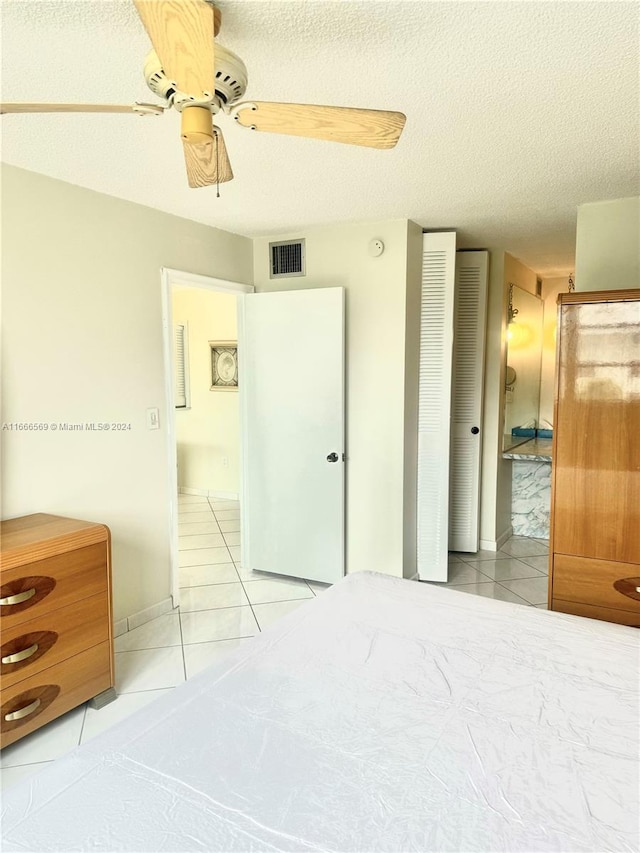 bedroom with a textured ceiling, light tile patterned floors, and ceiling fan