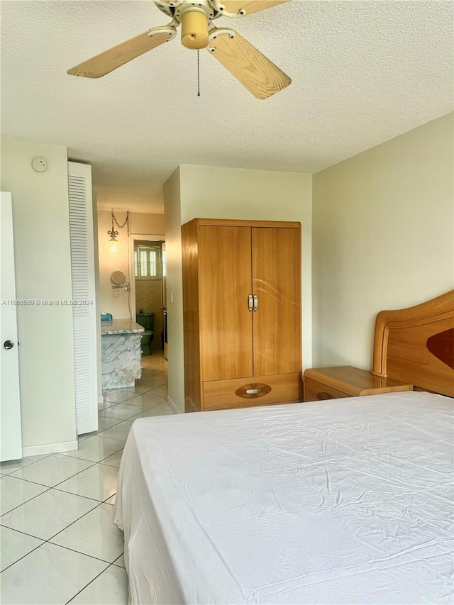 tiled bedroom with ceiling fan and a textured ceiling