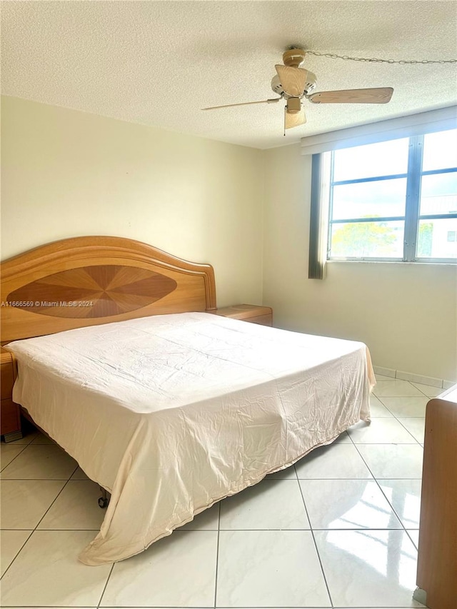 tiled bedroom featuring a textured ceiling and ceiling fan