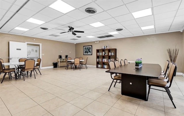 dining room with ceiling fan, a paneled ceiling, and light tile patterned floors