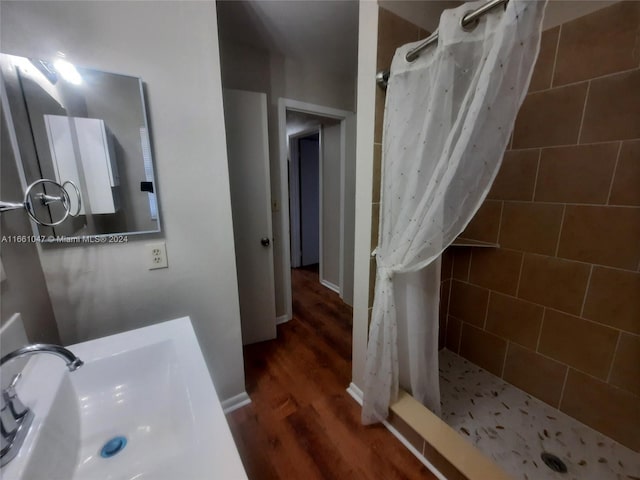 bathroom with wood-type flooring, a shower with shower curtain, and sink