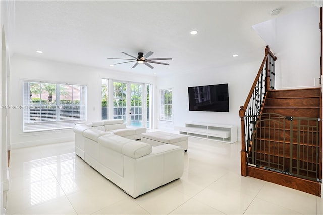 tiled living room with ceiling fan and crown molding