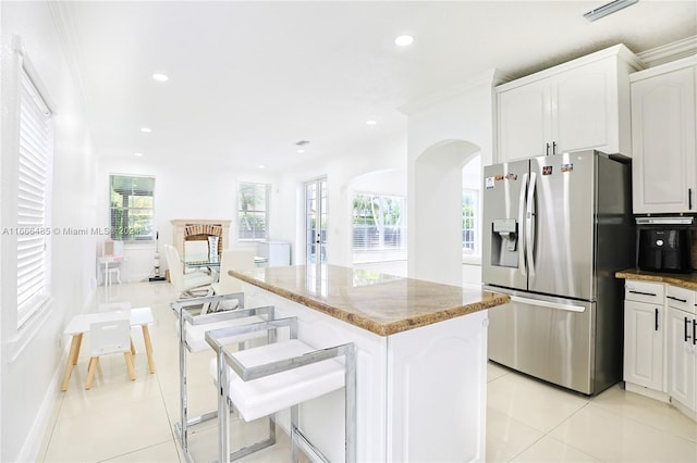 kitchen featuring a wealth of natural light, stainless steel fridge, ornamental molding, and a center island