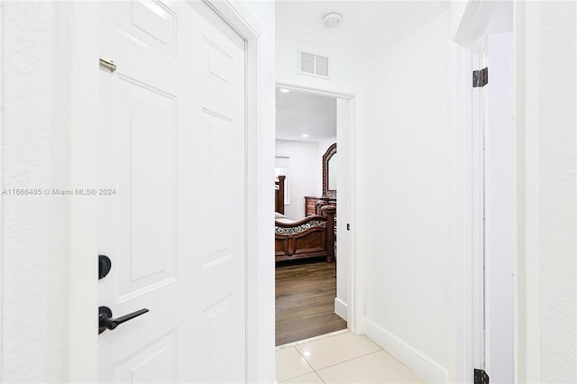 corridor featuring crown molding and light tile patterned floors