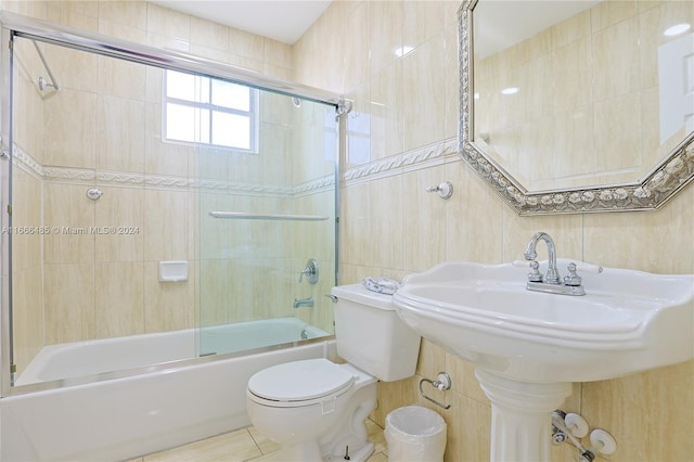 bathroom featuring tile walls, toilet, tile patterned floors, and combined bath / shower with glass door