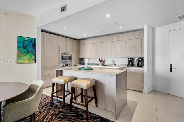 kitchen featuring stainless steel appliances, a kitchen breakfast bar, light countertops, a center island, and modern cabinets